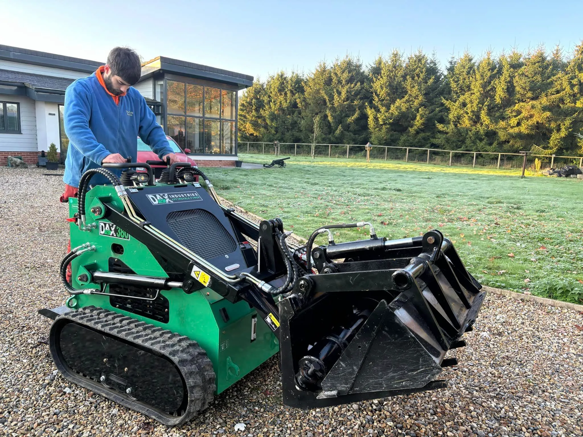 A man standing next to a green lawnmower.